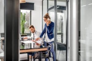 Productive office workers in room with ample natural light let in by sliding door system