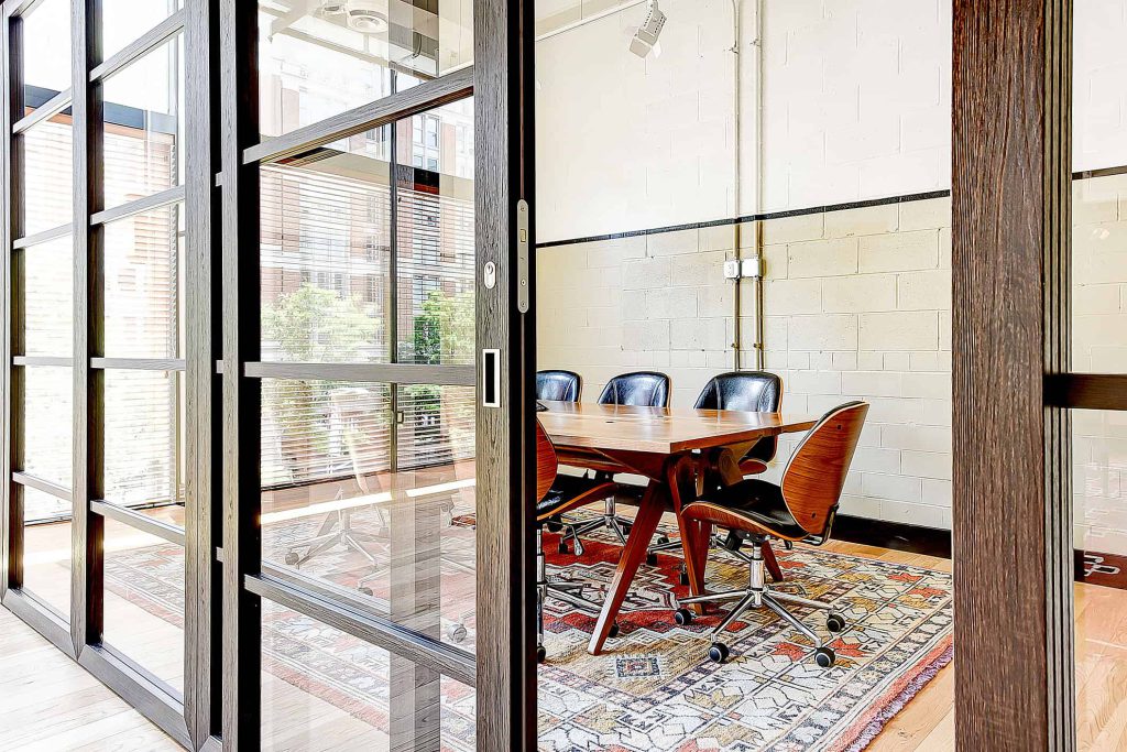 A series of transparent-paneled sliding doors wall off an intimate conference space from the rest of this commercial office