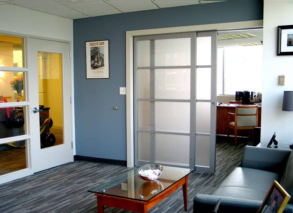 A translucent sliding door system separates a common waiting area from a private office environment.
