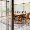 Inspiring office meeting space defined by a Raydoor sliding wall, featuring a mid-century table and chairs on an artistic rug.