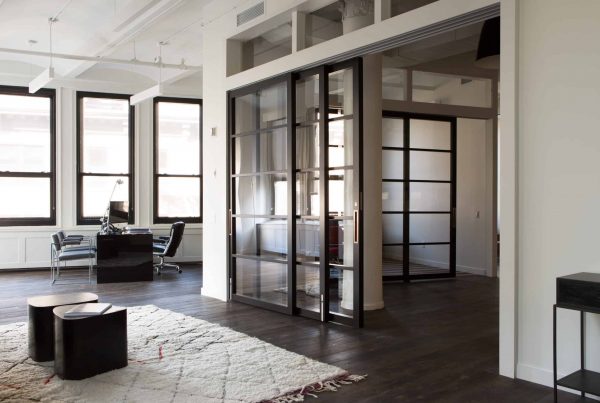 A modern office environment features group workstations, social gathering space, and a partitioned meeting area.