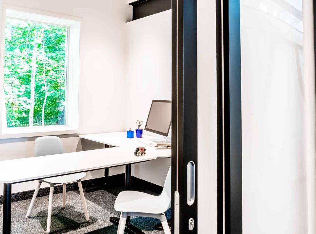 A sliding door system is partially open to reveal a small, individual office space.
