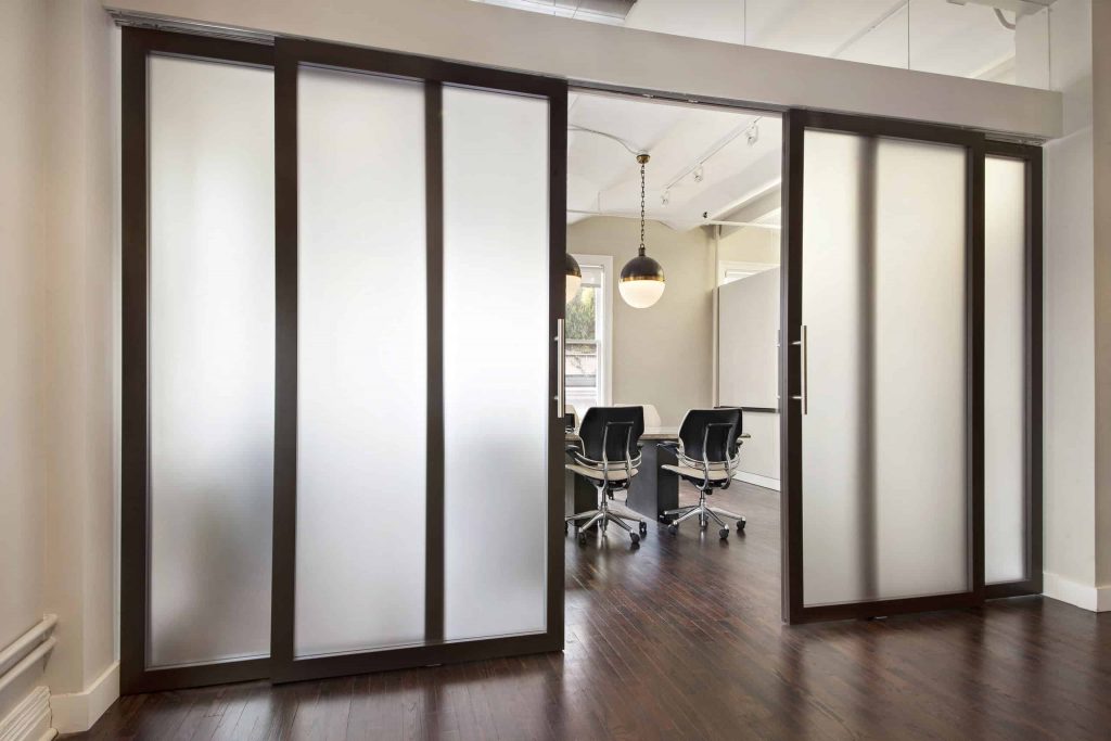 A partially open operable wall reveals a sleek conference room on the other side.