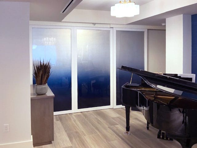 White opaque doors in a living room closed with a black grand piano in front of it.
