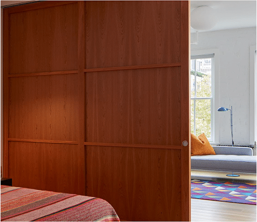 A wood-paneled sliding door creates total privacy between a bedroom and living space.