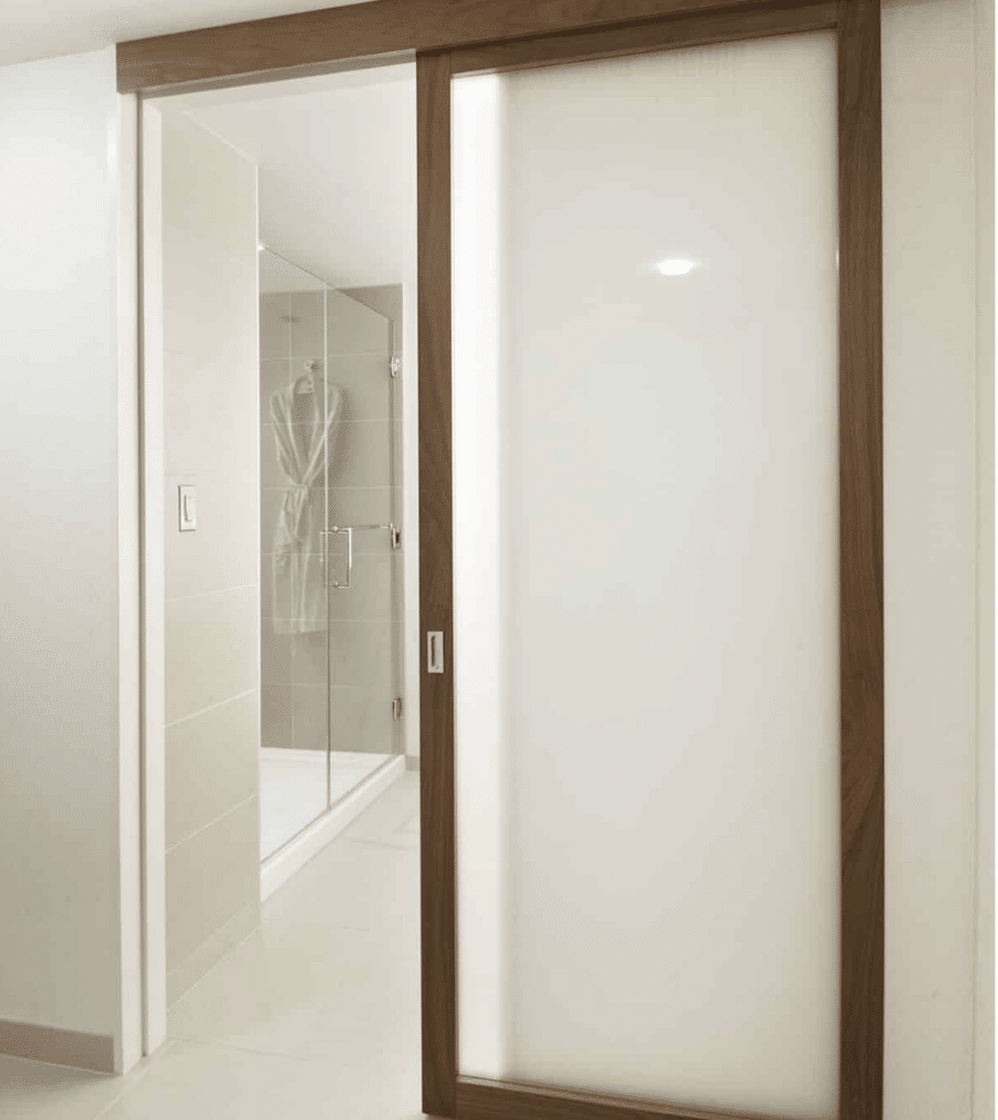 An open sliding door with a frosted insert divides a bathroom and the rest of a hotel suite.